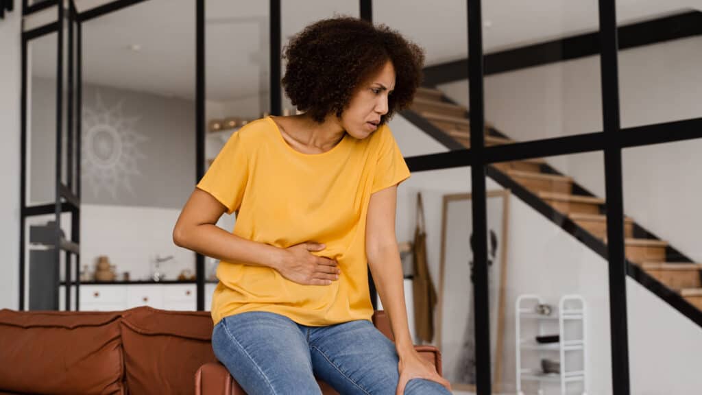 Black woman holding stomach.