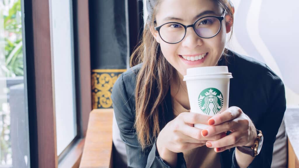 young Asian woman enjoying hot cup of coffee at Starbucks.