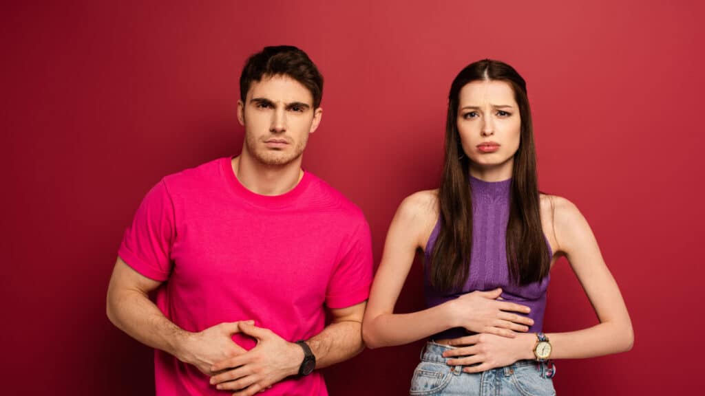 Young man and woman holding stomachs. Stomach ache.