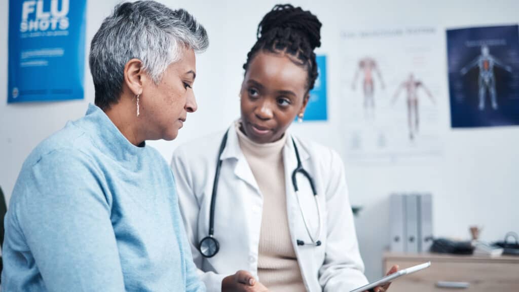 Black female doctor talking with older female patient.