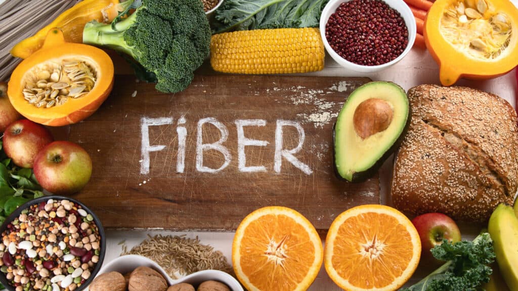 image of healthy fiber rich food on wooden board with word "Fiber" in center.