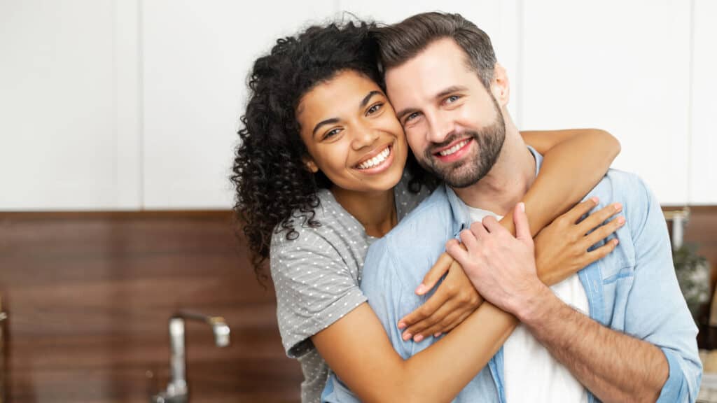 Interracial couple hugging and smiling.