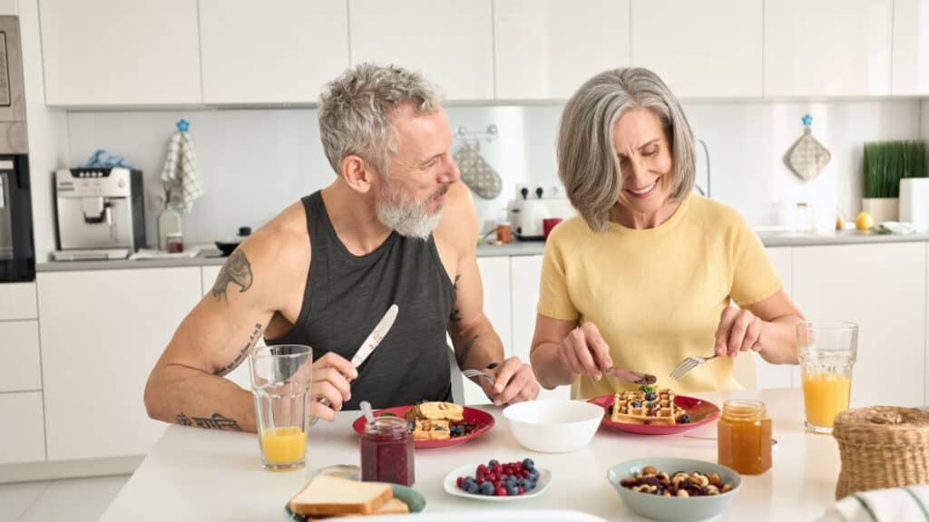 Mature couple in kitchen eating healthy food. 