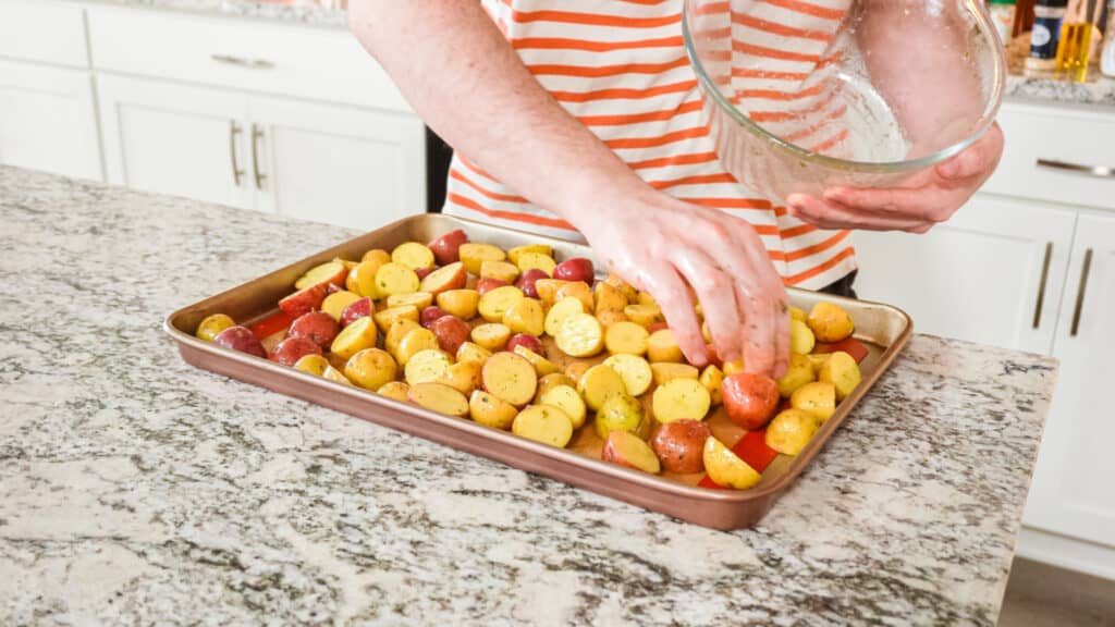 Person arranging potatoes on sheet pan. 
