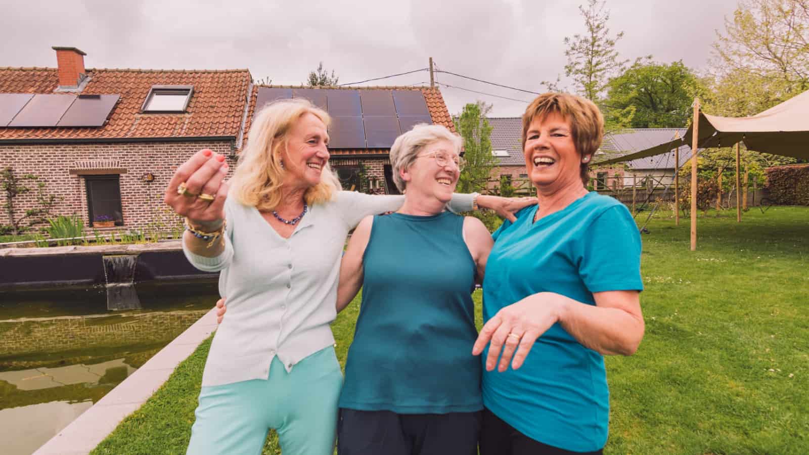 Three older women outside in a courtyard amongst suburban houses.