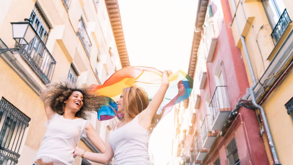  Two women holding pride flag aloft in streets of Madrid. Spain. 
