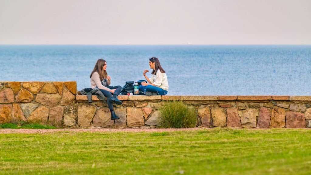 Two women sitting near the water in Montevideo Uruguay. 