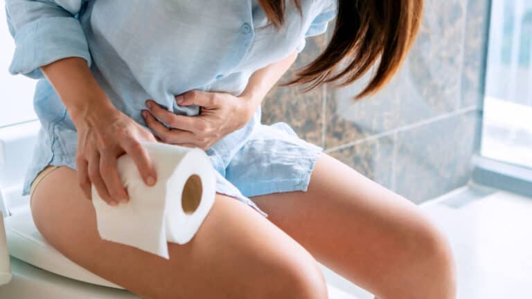 Woman on toilet. Clutching stomach.