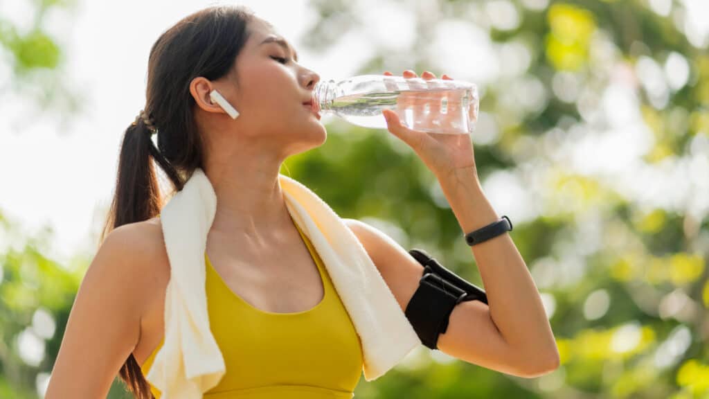 Young female athlete hydrating. Drinking water. 