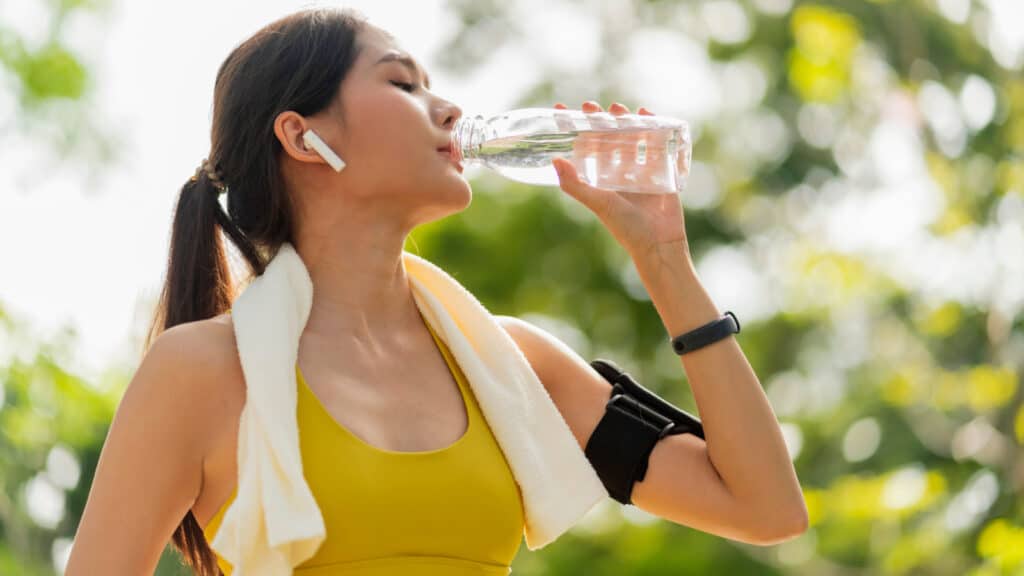 Young female athlete hydrating. Drinking water.