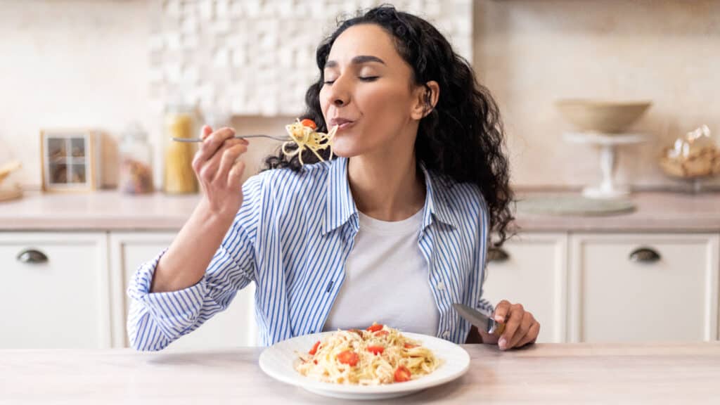 woman eating pasta at table. 