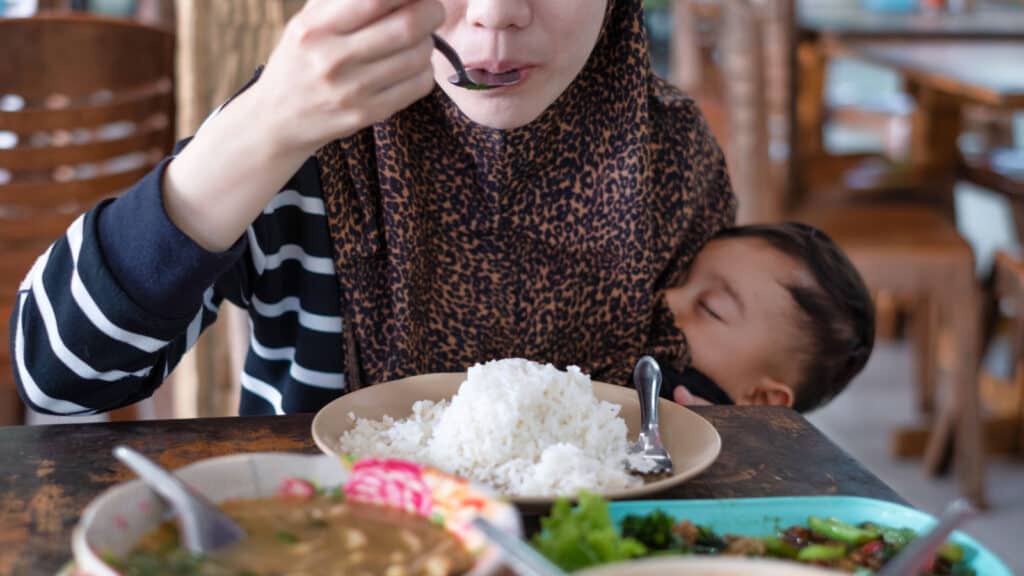 Asian woman eating while breastfeeding. Hungry woman. Baby.