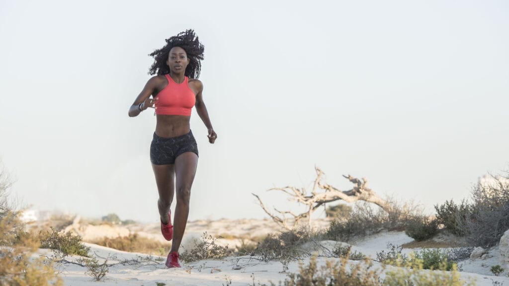 Black woman running in dunes.