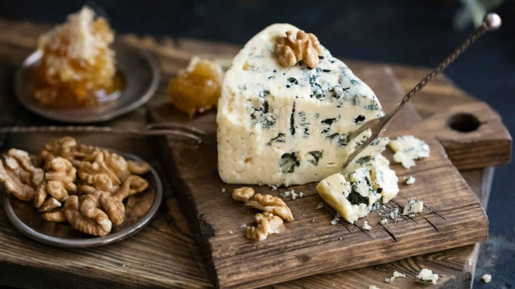 Blue cheese and walnuts on wooden board.