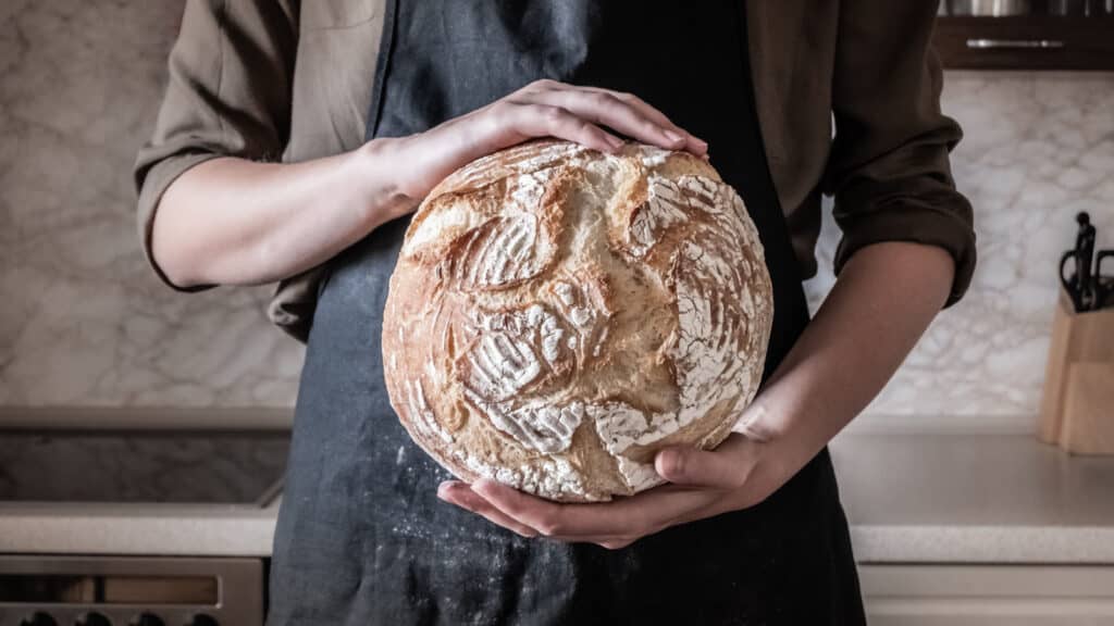 Hands holding round bread.