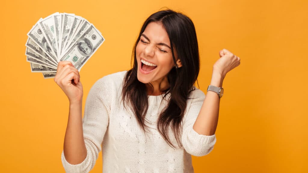 Happy woman holding a fan of paper money in hand.