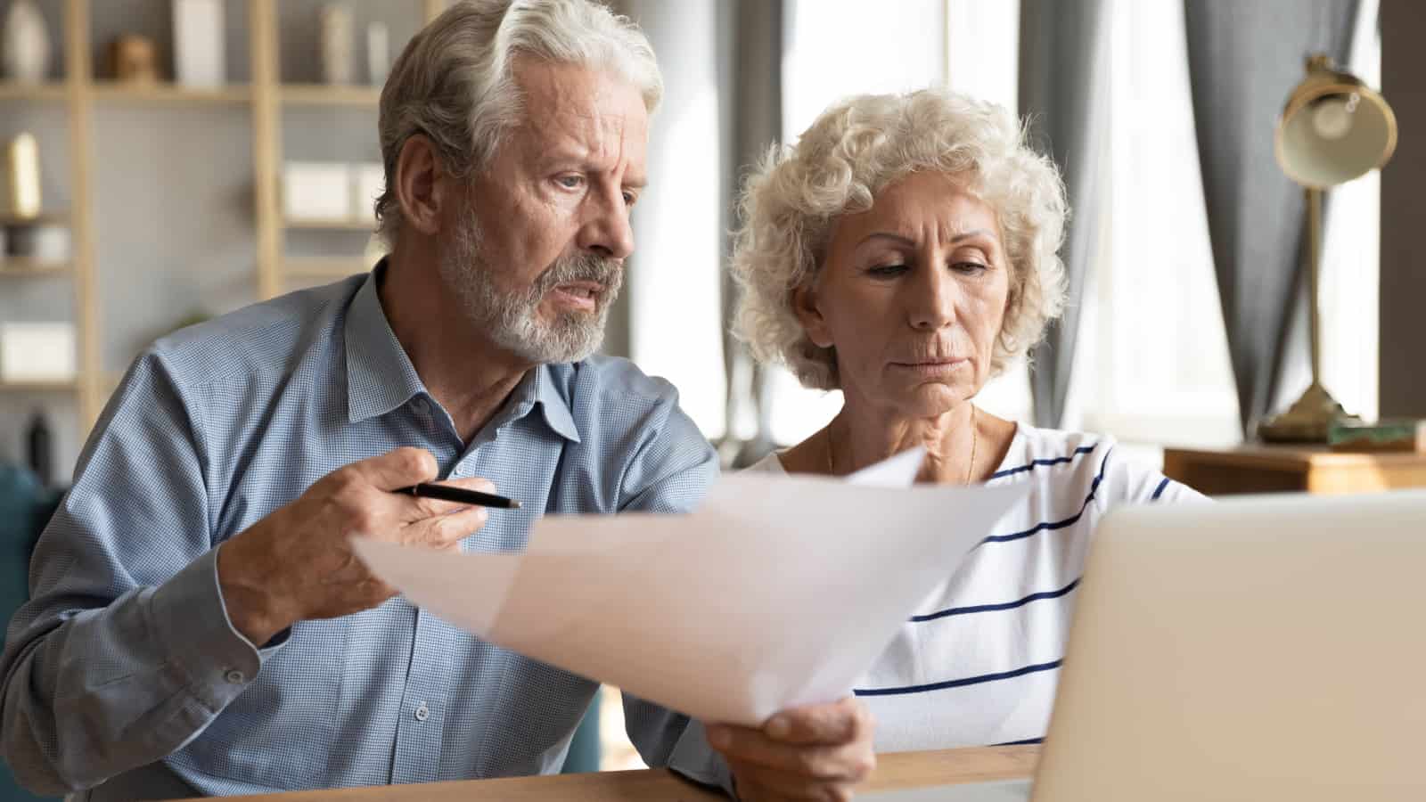 Older couple looking at paper and computer.