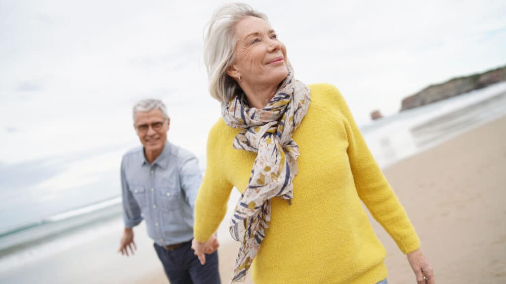 Older couple walking on beach.