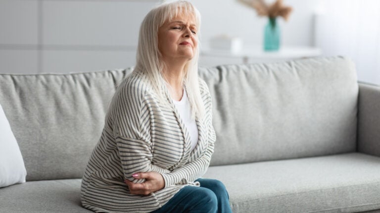 Older woman with IBS. Clutching stomach.