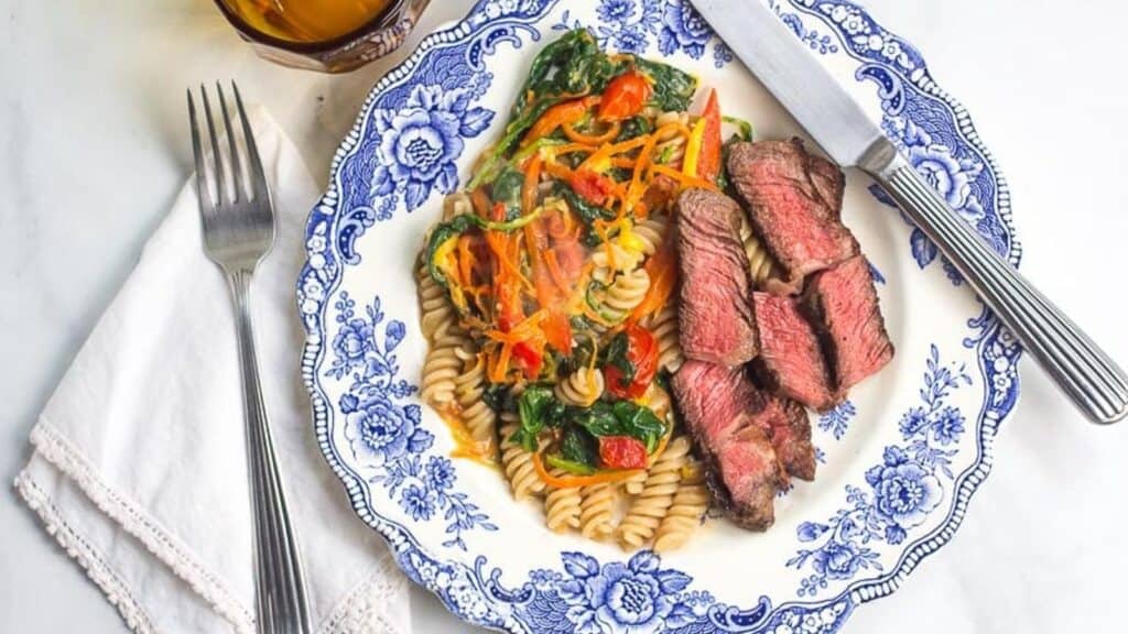 One-Pan-Low-FODMAP-Pasta-Vegetables-steak-alongside-on-blue-and-white-plate.