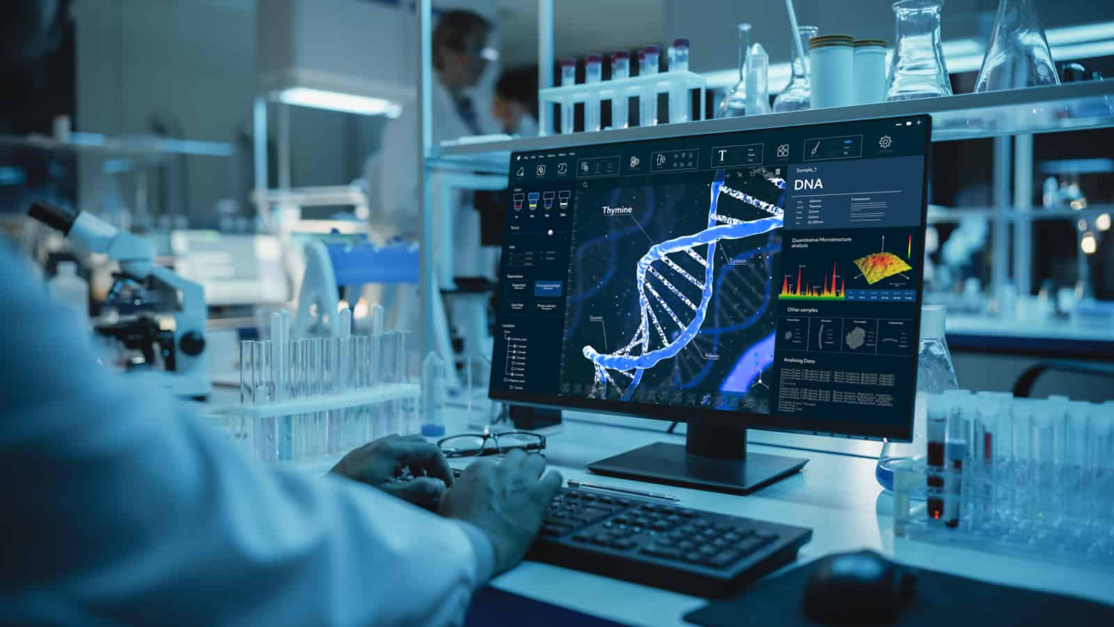Medical Research Scientist Working on Desktop Computer with Gene Analysis Software in Modern Science Research Laboratory. Lab Engineers in White Coats Conduct Experiments in the Background.