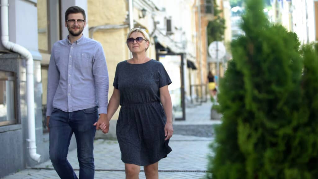 Mature woman walking on street with younger men, relations and connection couple