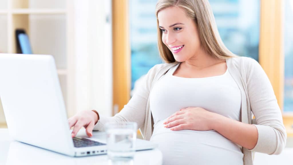 Pregnant woman sitting at computer desk.