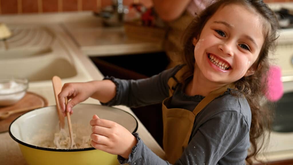 Smiling happy young girl, kid, child, cooking.