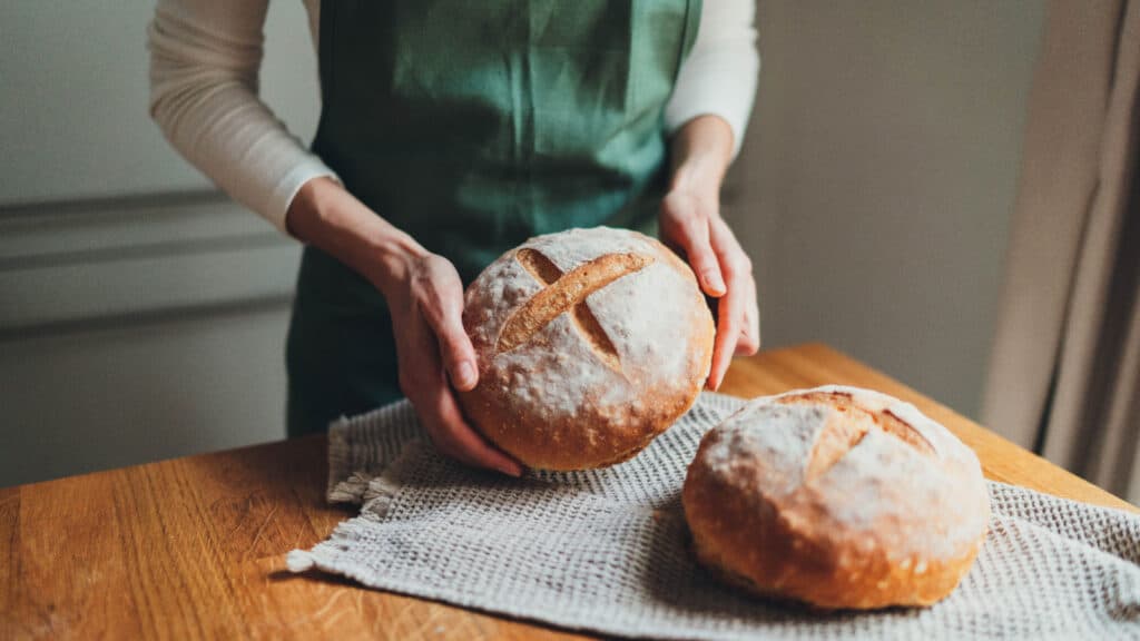 Woman holding round crusty bread. 