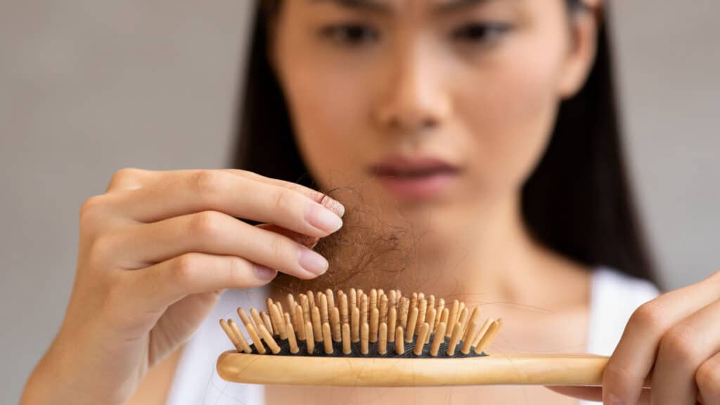 Woman looking at hair in brush.