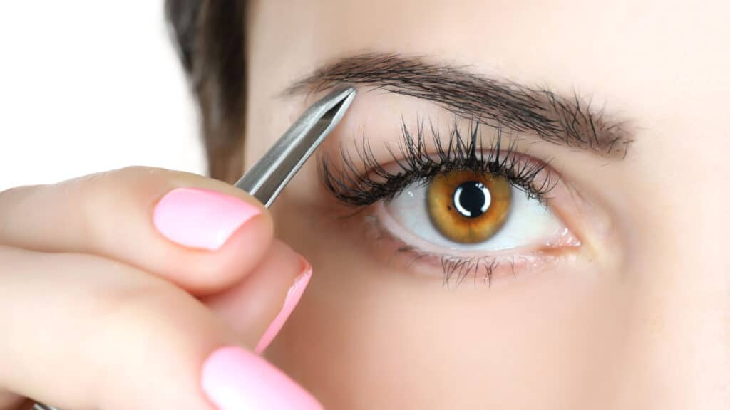 Woman plucking eyebrows.
