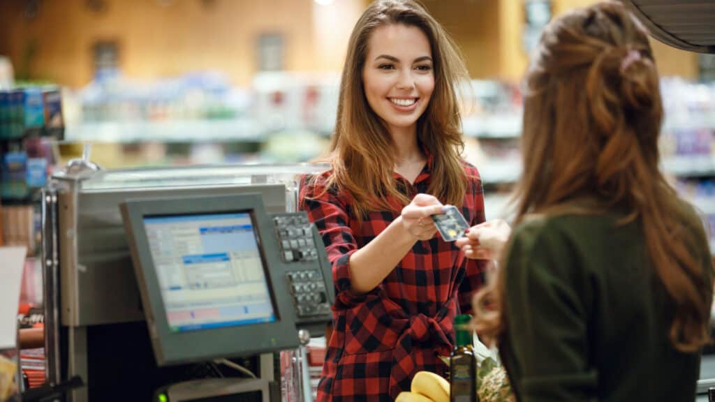 Woman using credit card at supermarket. 