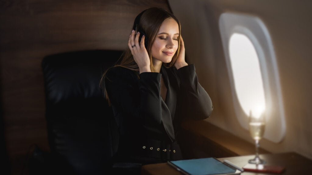 Women wearing headphones on plane, relaxing. Wireless headphones. 