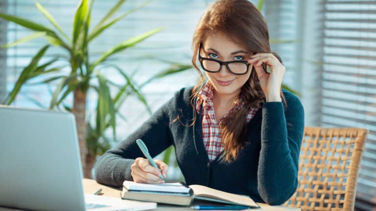 Young woman wearing glasses working at desk. Smart.