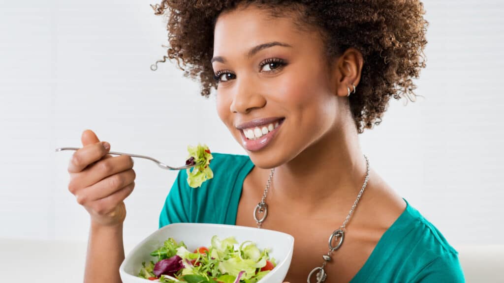 black woman eating salad. 