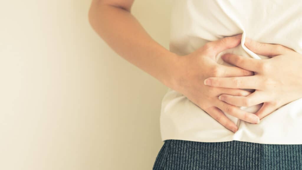 closeup of person clutching stomach. IBS. Tummy ache. 