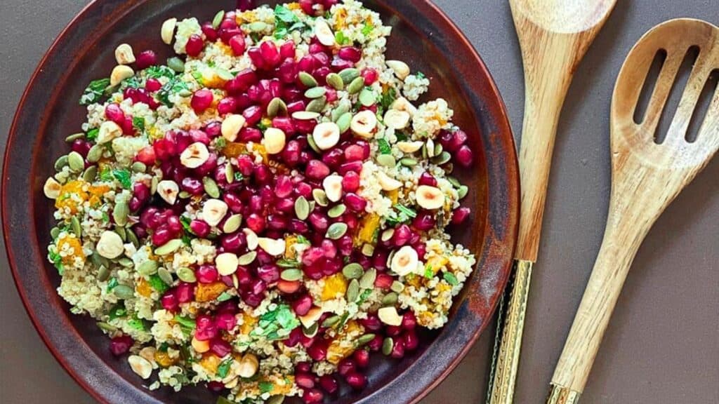 overhead-image-of-low-FODMAP-Roasted-Pumpkin-and-Quinoa-salad-with-pomegranate-seeds-and-nuts-on-brown-ceramic-plate.