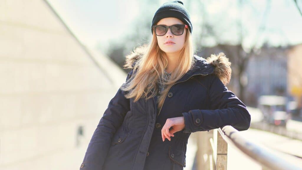 Woman in winter parka, hat and sunglasses.