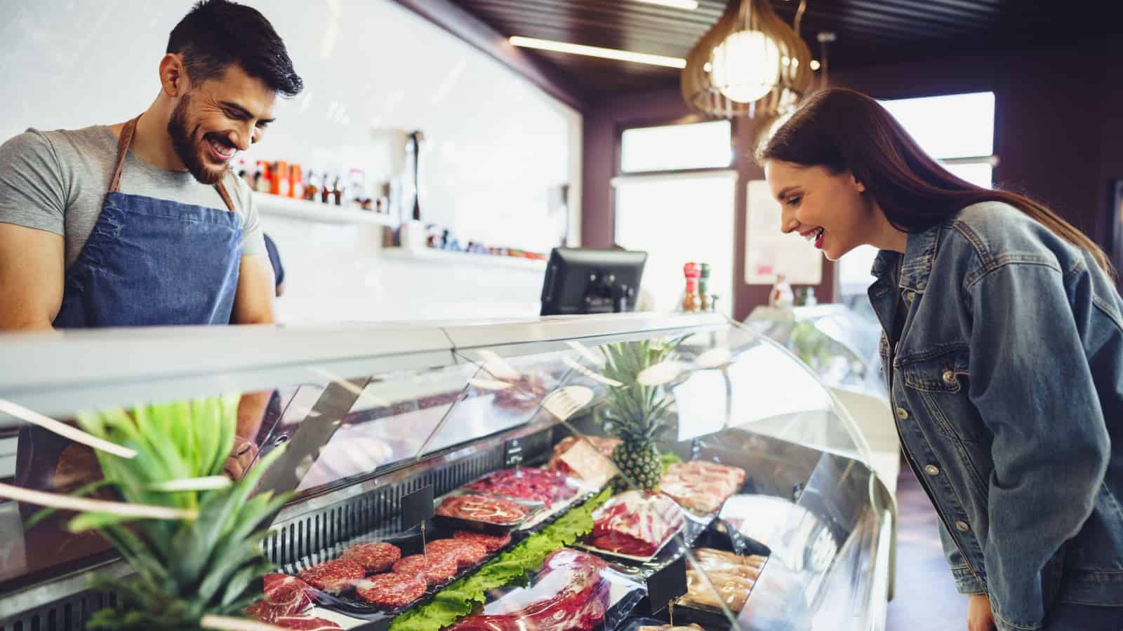 woman choosing meat at butcher shop. Meat counter.