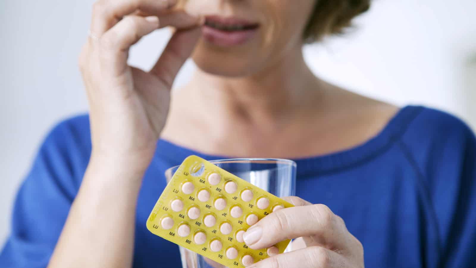 woman taking hormone replacement therapy. Pills.