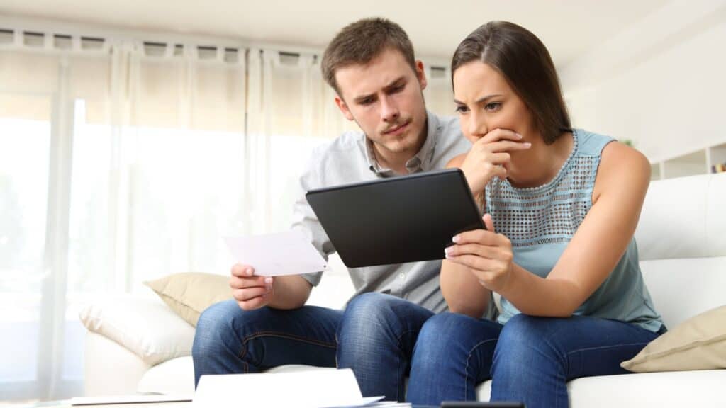 Couple looking at tablet looking worried. 