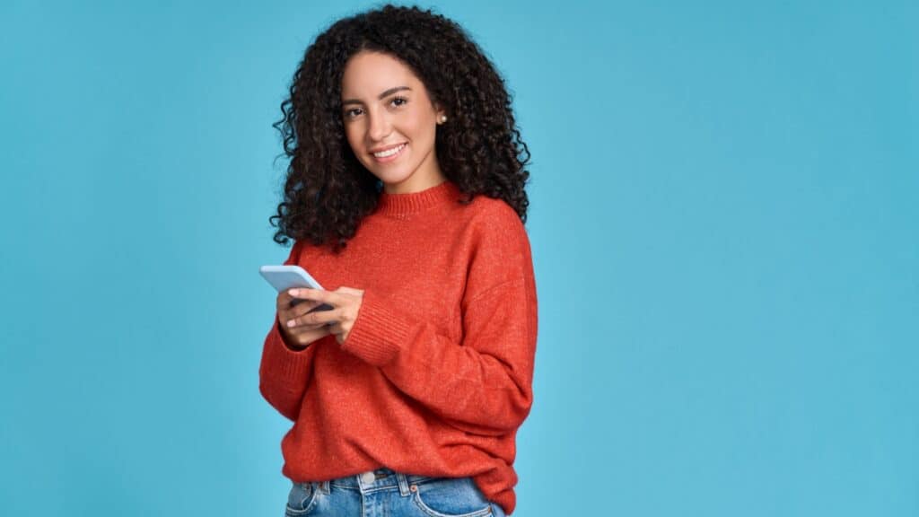 Happy woman with curly hair using phone.