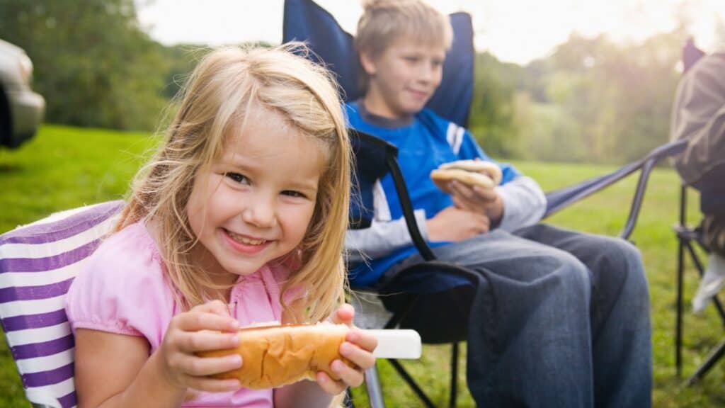 Kids enjoying hot dogs. 