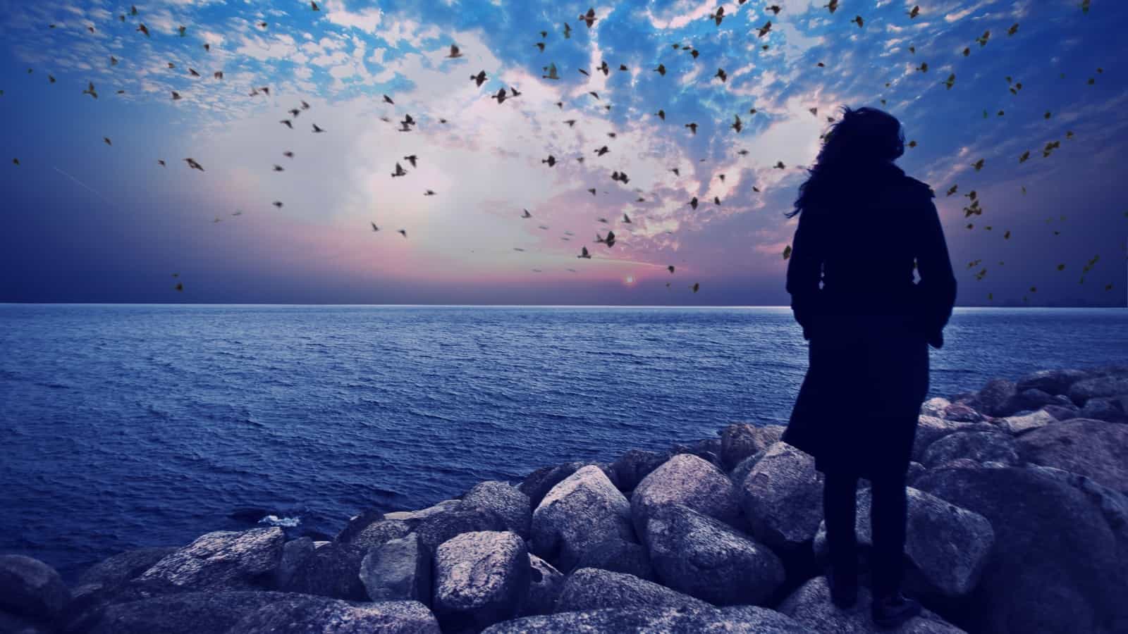 woman standing on the rocks watching sea sunset ,dramatic