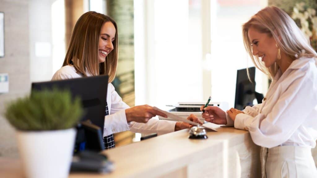 Receptionist and businesswoman at hotel front desk