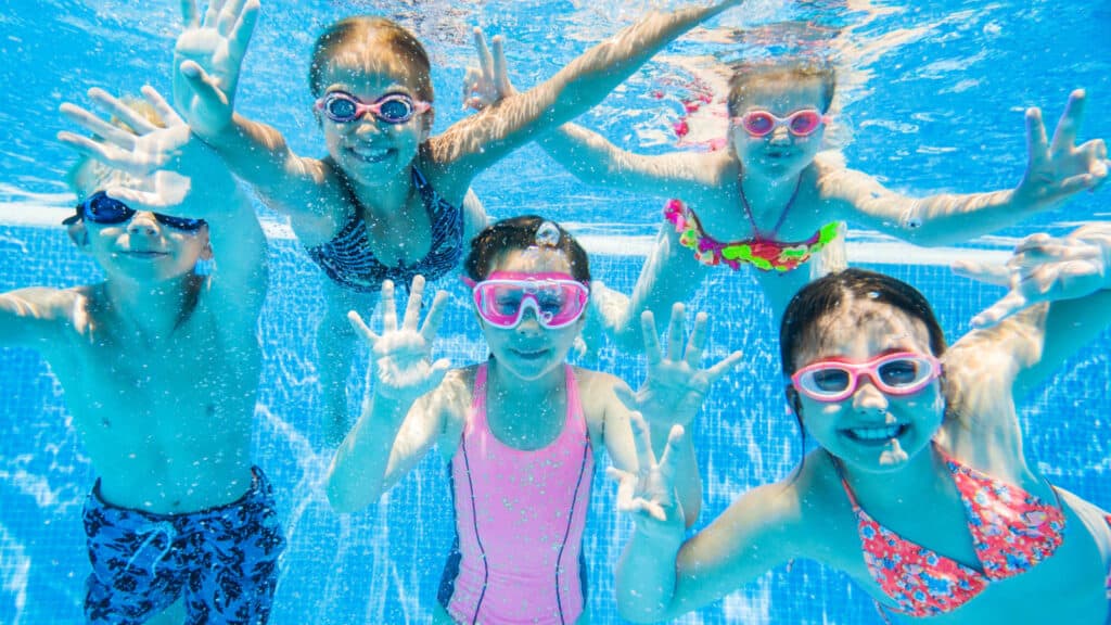 Smiling kids underwater in pool. 