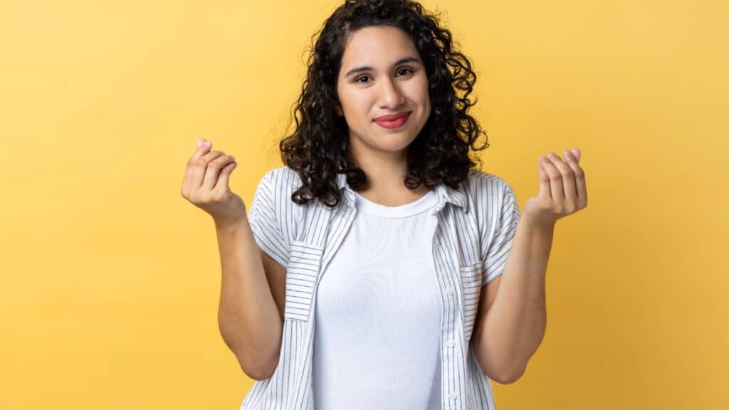 Woman making money sign, rubbing fingers together. 