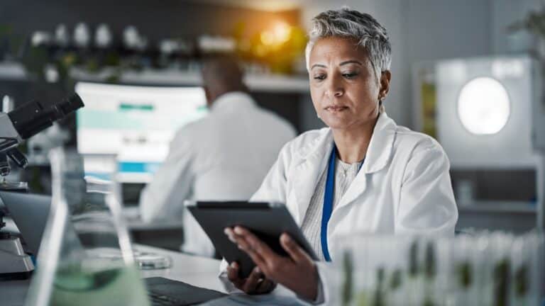 female scientist studying data on tablet.