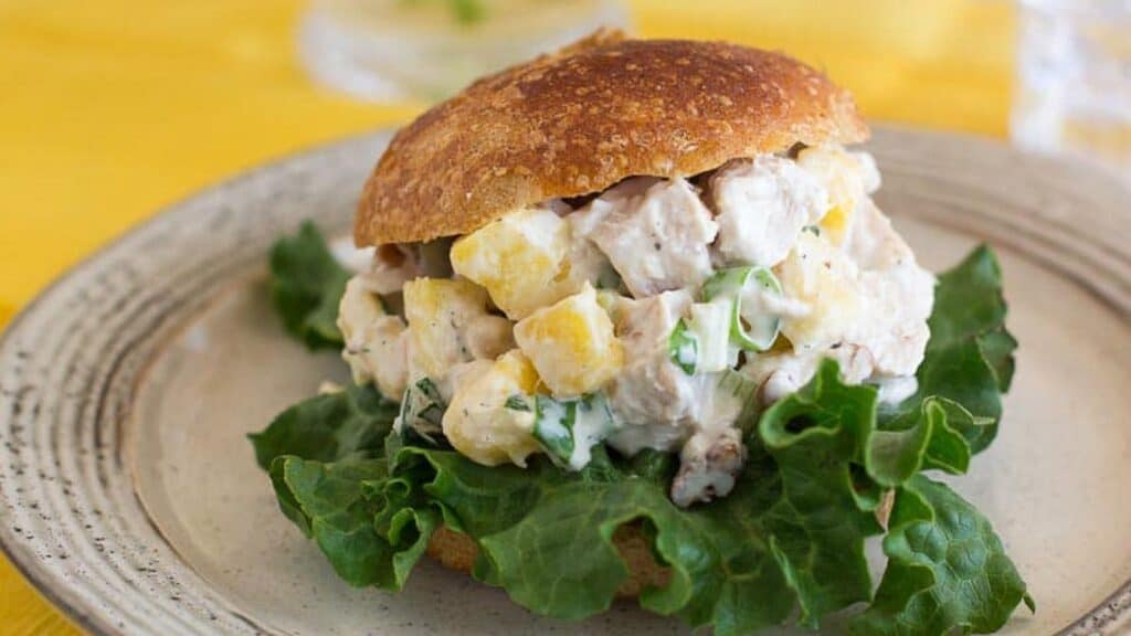 low-FODMAP-Pineapple-Chicken-salad-on-a-roll-with-yellow-napkin-in-background.