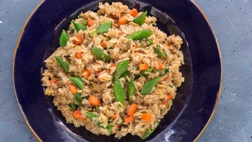 overhead-image-of-low-FODMAP-fried-rice-with-sugar-snap-peas-and-carrots-on-a-blue-plate.